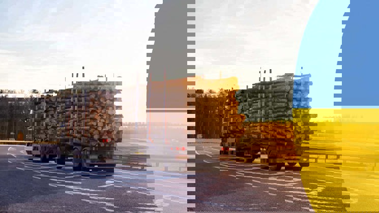 timmerlastbil på väg och en ukrainsk flagga