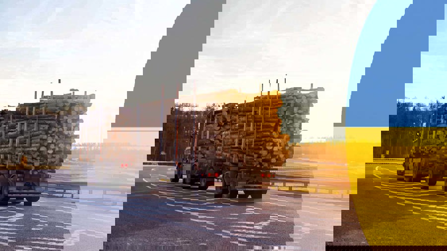 timmerlastbil på väg och en ukrainsk flagga